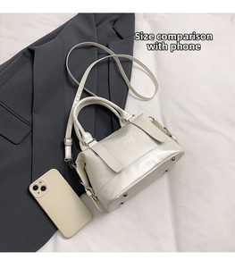 Confronto dimensioni di una mini borsa a tracolla bianco crema accanto a uno smartphone