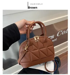 Detail view of brown quilted handbag with geometric stitching and gold metal zipper hardware