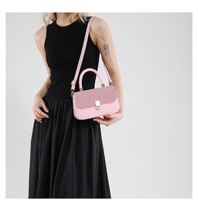 Detail of pink crossbody bag featuring glitter flap texture and golden twist lock closure