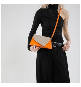 Detail van helder oranje driehoekige tas met textuur patchwork en een slanke leren riem