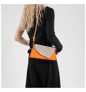 Detail van een moderne oranje lederen en beige geweven crossbodytas gedragen door model