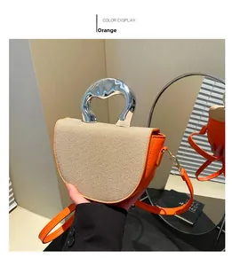 Détail du sac selle en cuir orange et tissu tissé beige avec poignée en métal argent