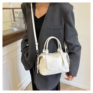Dettaglio di una borsa Boston bianca con scritte a rilievo e tracolla regolabile chic