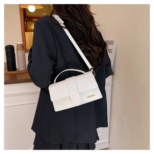 Petit sac à bandoulière en cuir blanc avec lettres dorées porté par un mannequin