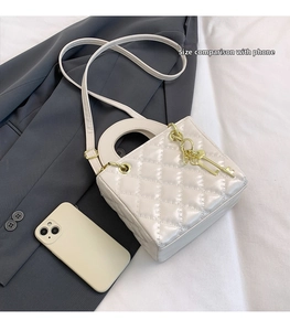 Quilted white crossbody bag shown next to a smartphone to demonstrate the small size