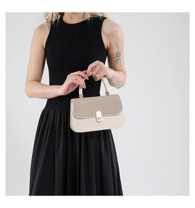 Detail of elegant cream leather handbag with woven texture flap and gold turn-lock closure