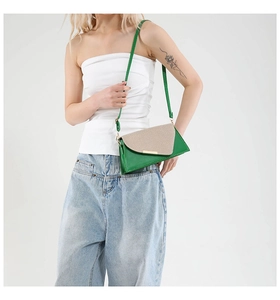 Detail van groene crossbodytas met beige geweven flap en goudkleurig metalen accent