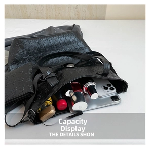 Spacious black leather tote with skull embossing holding an umbrella, phone and cosmetics
