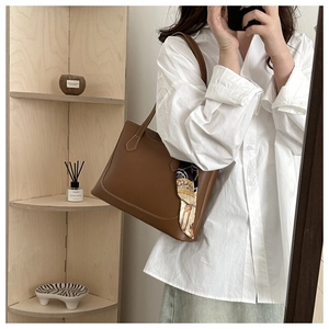Détail d'un grand sac fourre-tout en cuir marron avec un foulard en soie sur la poignée