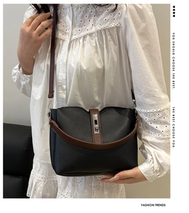 Detail of minimalist bucket bag with contrast brown straps and silver metal swivel lock