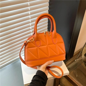 Orange geometric quilted shell handbag with dual top handles and gold hardware straps