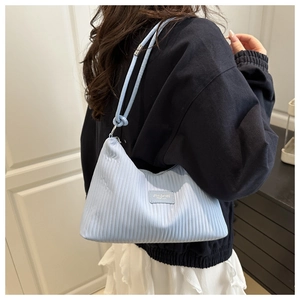 Detail of light blue pleated hobo bag with knotted strap and branding tag on the model