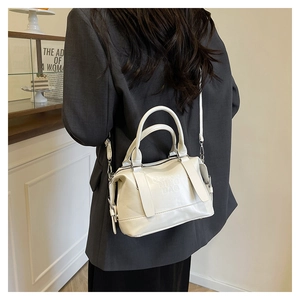 Dettaglio della borsa Boston bianca con logo a sbalzo indossata da modella in blazer grigio