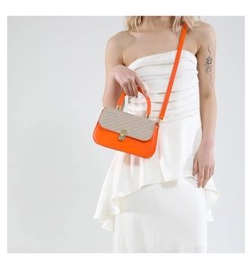 Detail of orange handbag featuring a grey woven flap, gold lock and metal handle