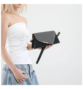 Detail van een moderne geometrische crossbodytas met zwart-grijze flap en lederen riem