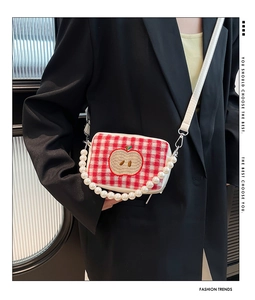 Detail of red plaid crossbody bag with apple embroidery and elegant pearl handle