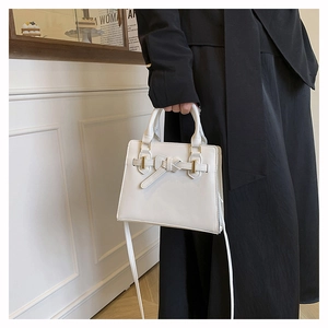 Detail of white handbag with elegant bow strap, gold metal buckle and adjustable strap