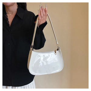 Detail of white glossy patent leather shoulder bag with gold hardware and zipper