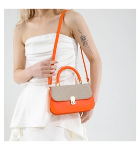 Detail of orange leather crossbody bag with beige woven texture and gold metal buckle