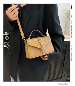 Détail du sac à main jaune à motif crocodile avec boucle sur fond de blazer noir