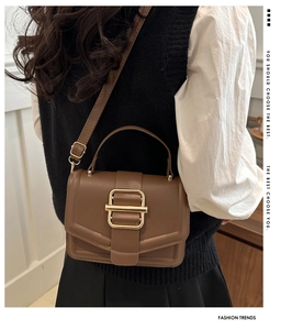 Détail du sac à main vintage en cuir marron foncé avec boucle dorée et bandoulière