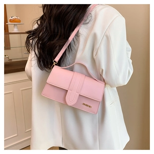 Détail d'un sac bandoulière en cuir rose avec coutures et logo en métal doré