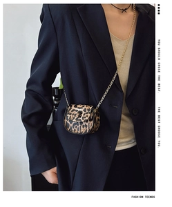 Detailed close-up of a mini leopard print saddle bag with a gold chain strap on a blazer