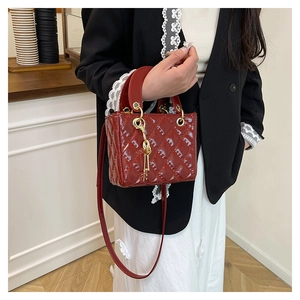 Detailed view of red patent leather quilted mini bag with golden key pendant charm