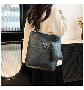 Macro detail of black tote bag with embossed skull pattern and metallic skull buckle