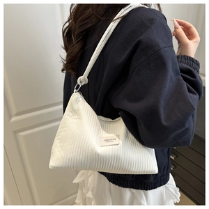 Detail of white corduroy shoulder bag with pink leather label and cylindrical strap