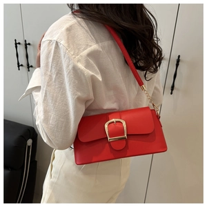 Detail of red leather shoulder bag with gold square buckle shown on model in modern setting