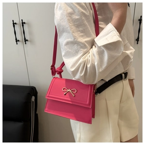 Bolso fucsia con lazo dorado combinado con camisa blanca y pantalones cortos beige