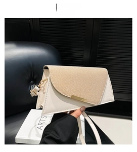 Detail van off-white crossbody tas met flap van strotuctuur en gouden gesp