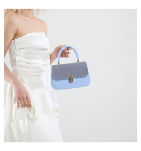 Détail du sac bandoulière bleu clair avec texture tissée grise et boucle en métal doré