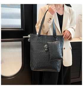 Detail of black tote bag with skull embossing and metallic skull charm with a small pouch