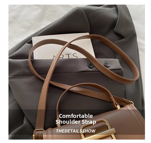 Detail of slim brown leather strap with golden metal buckle on a stylish crossbody bag