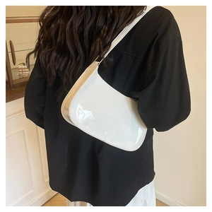 Glossy white patent leather baguette shoulder bag shown on model with minimalist retro style