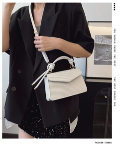 Détail du sac à main blanc tressé avec poignée nouée et finitions en métal doré
