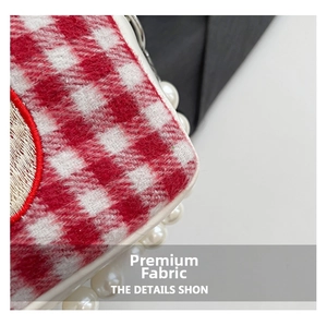 Detail view of red and white plaid tweed handbag with large pearl chain and embroidery