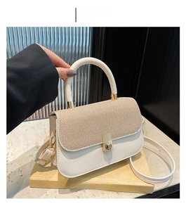Détail du sac à rabat blanc crème montrant la texture tissée et le fermoir doré rotatif