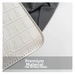 Vue macro de la texture cuir crocodile blanc et des coutures soignées sur le sac à main