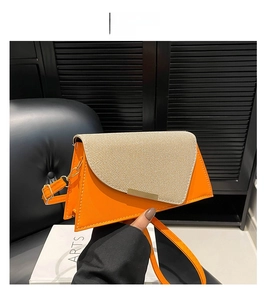 Detail van de oranje leren en beige geweven tas met goudkleurige versiering
