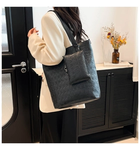 Detail of black embossed skull tote bag and matching pouch shown on a shoulder