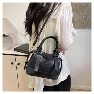 Dettaglio borsa nera in similpelle con logo a rilievo e fibbie metalliche argentate