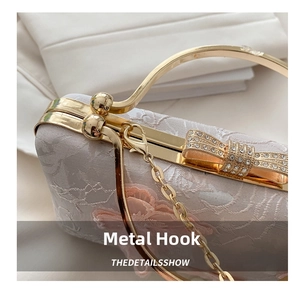 Detail of lace evening bag with butterfly clasp and golden chain strap attachment