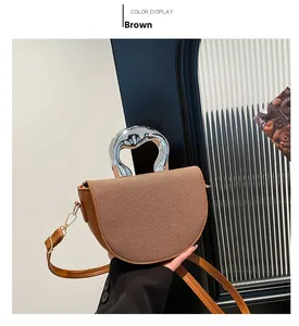Détail du sac selle marron avec texture tissée et poignée en métal argenté unique