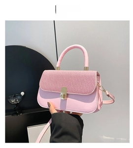 Détail d'un sac rose avec rabat tissé et fermoir rotatif métallique doré chic