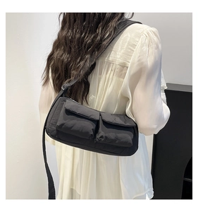 Detail of black nylon crossbody bag featuring double front flap pockets and wide strap