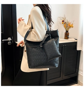 Detail of black tote bag set with embossed skull pattern and matching small pouch