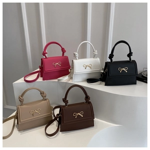 Detailed arrangement of bow crossbody bags in magenta, white, black, and khaki on a pedestal